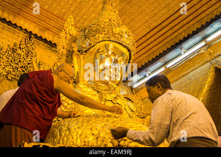 L'application de la feuille d'or à un immense Bouddha d'or, statue de Mahamuni l'un des plus vénérés de Bouddhas en Birmanie, Birmanie Mandalay.,Myanmar. Banque D'Images