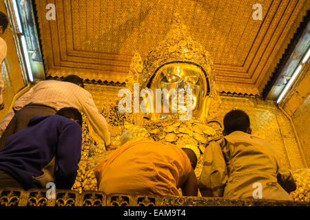 L'application de la feuille d'or à un immense Bouddha d'or, statue de Mahamuni l'un des plus vénérés de Bouddhas en Birmanie, Birmanie Mandalay.,Myanmar. Banque D'Images