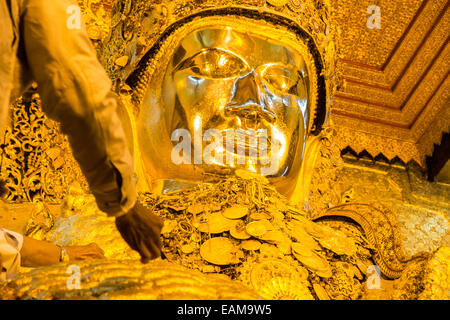 L'application de la feuille d'or à un immense Bouddha d'or, statue de Mahamuni l'un des plus vénérés de Bouddhas en Birmanie, Birmanie Mandalay.,Myanmar. Banque D'Images