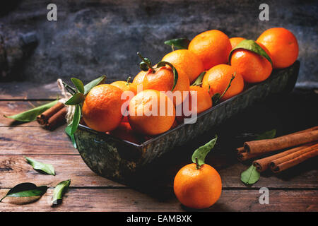 Mandarines avec les feuilles et le bâton de cannelle sur la vieille table en bois. Banque D'Images