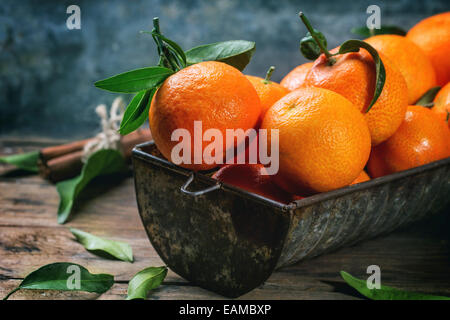 Mandarines avec les feuilles et le bâton de cannelle sur la vieille table en bois. Banque D'Images