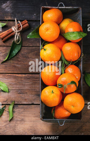 Mandarines avec les feuilles et le bâton de cannelle sur la vieille table en bois. Vue d'en haut. Banque D'Images