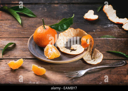 Ensemble, avec les feuilles et les couper les tangerines sur plaque en céramique plus vieille table en bois. Banque D'Images