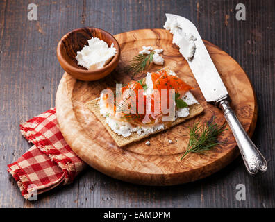 Sandwich sur du pain croustillant de saumon fumé et fromage à la crème douce sur plaque de bois d'olive Banque D'Images