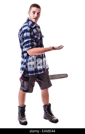 Un jeune bûcheron portant une chemise à carreaux à la main une scie à chaîne et montrant quelque chose d'isolé sur fond blanc Banque D'Images