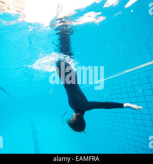 Plongeur femelle calmement vers le bas à travers la plongée en piscine de surface Banque D'Images