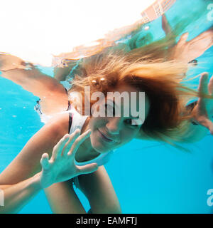 Jolie femelle avec les yeux ouverts à la recherche et souriant alors que sous l'eau à la piscine Banque D'Images