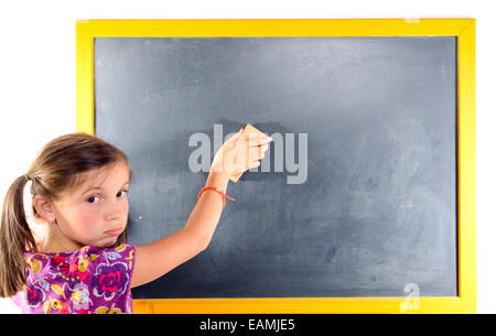 Une petite fille avec des nattes écrit sur un tableau noir Banque D'Images