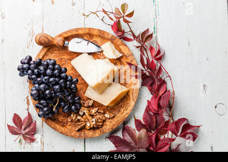 Le Parmesan, les raisins et les noix sur la plaque en bois d'olivier Banque D'Images