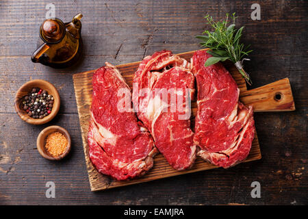 Ribeye steak cru viande fraîche et l'assaisonnement entrecôte sur fond de bois foncé Banque D'Images