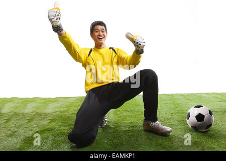 Un joueur de football s'agenouilla sur l'herbe de gestes Banque D'Images