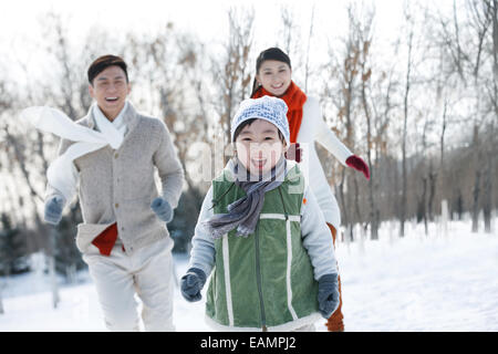 La famille de l'enfant uniquement en marche dans la neige Banque D'Images