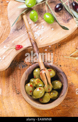 Olives vertes avec bol en bois d'olive et de piment sur la direction générale de la table en bois. Banque D'Images