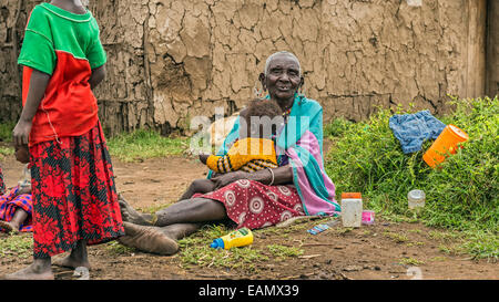 Vieille femme africaine à partir de la tribu Masai tenant un bébé dans son village Banque D'Images