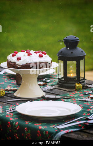 Réglage de la table de Noël en plein air avec du chocolat Gâteau cerise. Banque D'Images