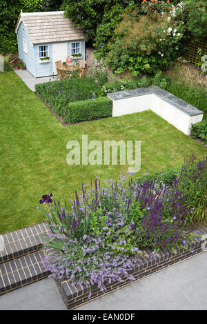 Soulevées bed construit en brique gris violet et rouge foncé avec la plantation avec playhouse de coin dans le jardin moderne, Londres Banque D'Images