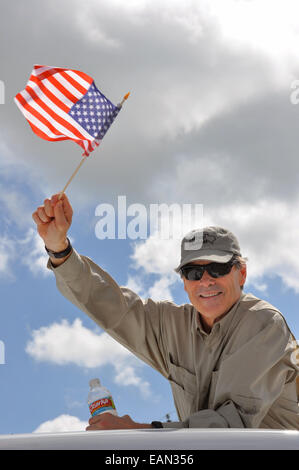 Le gouverneur du Texas, Rick Perry, vagues un drapeau américain lors de commémorations de l'indépendance le 4 juillet 2010 à Round Top, Texas. Banque D'Images