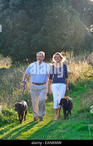 A mature couple promènent leurs chiens sur les South Downs, Eastbourne. East Sussex, UK Banque D'Images