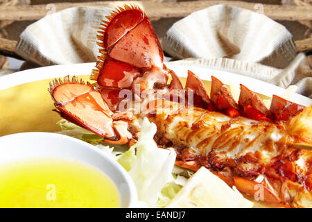 Brochettes de queue de homard principal dans le shell frit avec flash et beurre Citron Citrons et laitue sur une plaque d'or Banque D'Images