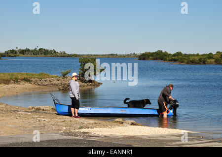 Homme, femme et son chien se préparent à aller à la pêche dans un petit bateau Banque D'Images