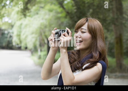 Une femme dans un parc de Kyoto tenant une caméra. Banque D'Images