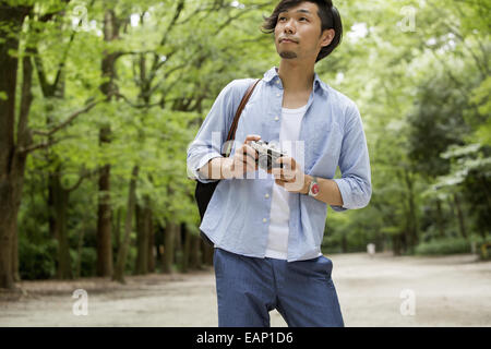 Un homme dans un parc de Kyoto tenant une caméra. Banque D'Images