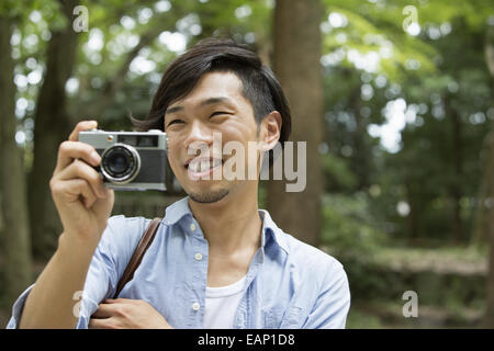 Un homme dans un parc de Kyoto tenant un appareil photo, prendre une photo. Banque D'Images