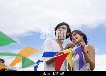 Un couple, un homme et une femme dans un parc de Kyoto brandissant une rangée de drapeaux colorés. Banque D'Images