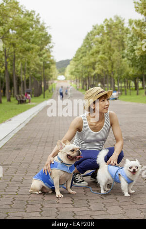 Femme marche deux chiens sur un chemin pavé. Banque D'Images
