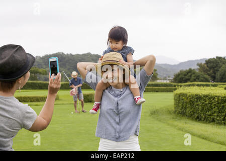 Famille sur un terrain de golf. Un enfant sur les épaules d'une femme. Banque D'Images