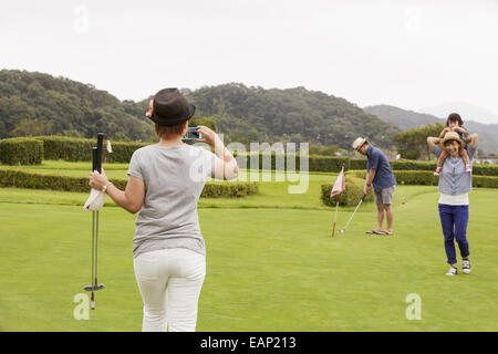 Sur un terrain de golf de la famille.Un enfant et trois adultes. Une femme avec un appareil photo. Banque D'Images