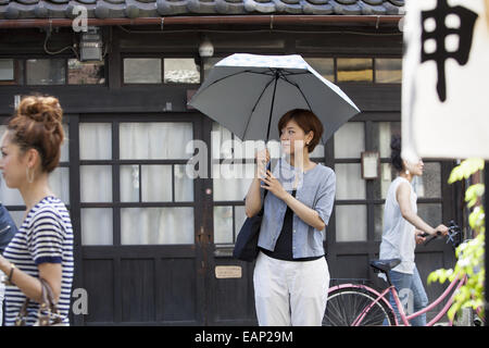 Femme debout à l'extérieur, tenant un parapluie. Banque D'Images