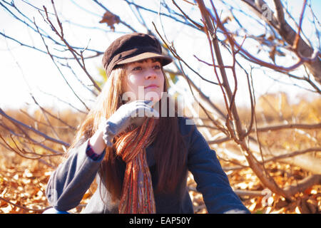 Fille avec regard pensif assis près d'un arbre sur une journée ensoleillée à l'automne Banque D'Images