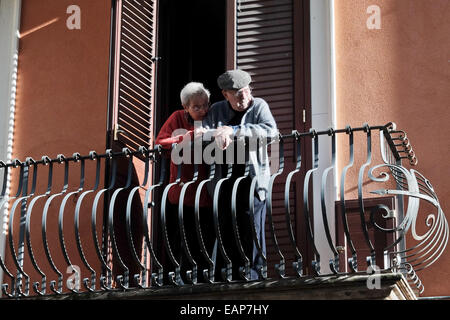 Un couple de personnes âgées vues le flux de touristes dans la rue en dessous de leur balcon du deuxième étage dans la ville de Taormina. Niché sur les pentes de la montagne sur la côte est de la Sicile, Taormina tourisme sert à la fois pour sa propre splendeur et qu'un point de saut à l'Etna. La Sicile avec quatorze pour cent du taux de chômage, l'un des plus élevés en Italie, des navigateurs de l'économie se tournent vers le tourisme comme une source importante de revenus dans l'avenir tout au long de l'île. Banque D'Images