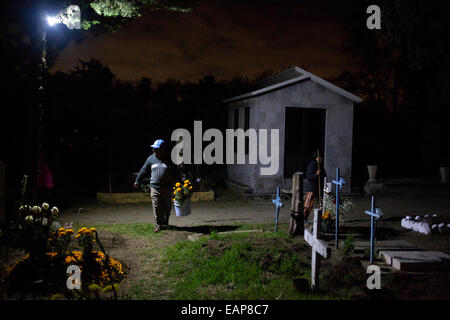 Un homme porte des fleurs de souci jaune, connu sous le nom de bougies, et chargés de décorer une tombe au cimetière de San Gregorio, Mexique Banque D'Images