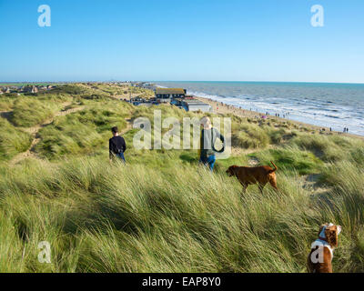 Un couple marche leurs chiens sur les dunes de sable à Camber Sands, Romney Marsh, près de Rye, East Sussex Banque D'Images