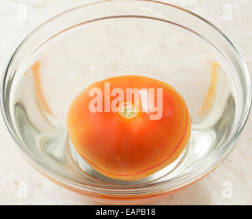 La tomate dans bol d'eau avec séparation de la peau Banque D'Images