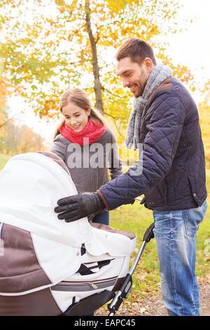 Smiling couple avec bébé la pram in autumn park Banque D'Images