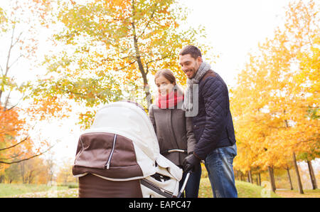 Smiling couple avec bébé la pram in autumn park Banque D'Images