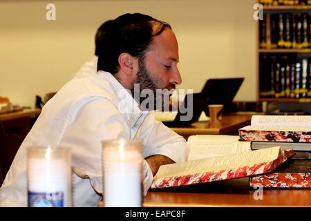 Un jeune homme juif orthodoxe se trouve à l'intérieur du B'nai Torah Synagogue Kehillat Yeshiva lire un livre saint.un jour après une attaque par deux hommes palestiniens sur une synagogue juive à Jérusalem dans le quartier de Har Nof, qui a tué quatre rabbins, dont trois étaient des citoyens américains, et l'un qui était un immigrant britannique, et un agent de la police israélienne, les gens se sont réunis dans une ambiance calme et sombre en face de la Kehillat nai Torah Synagogue talmudique et dans le quartier palestinien des deux hommes qui étaient les assaillants pour pleurer les victimes. © PACIFIC PRESS/Alamy Live News Banque D'Images