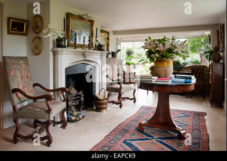 Paire de fauteuils sculptés du 19ème siècle cheminée en pierre d'accompagnement en chambre avec table circulaire et dorure d'art encadrées Banque D'Images