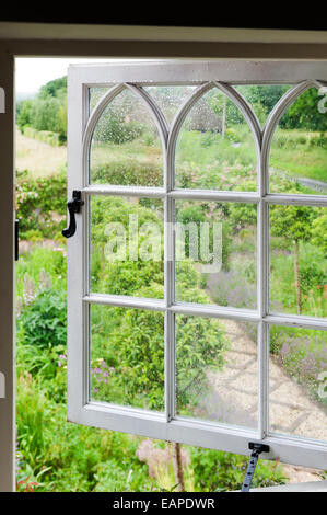 Vue à travers la fenêtre de style gothique ouvert sur jardin verdoyant Banque D'Images