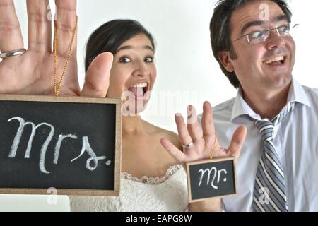 Nouvelle mariée hispanic couple holding signs disant ' Mr' et ' Mme' dans leurs mains. Banque D'Images