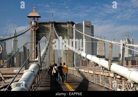 NYC : personnes marchant le long de la voie piétonne en bois au sommet de la 1875 Pont de Brooklyn avec sa célèbre tour ouest gothique Banque D'Images