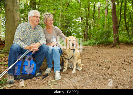 Happy senior couple avec chien en prenant une pause dans une forêt Banque D'Images