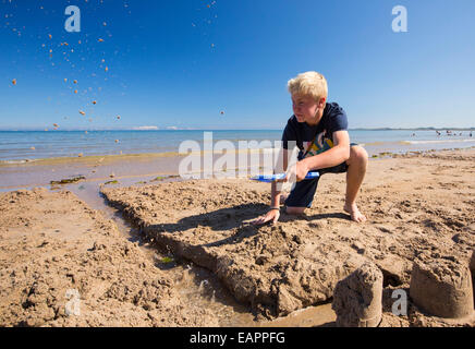 La construction d'un château de sable un garçon sur la plage de Bamburgh, Northumberland, Angleterre. Banque D'Images