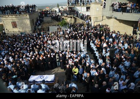 Jérusalem, Yanuh-Jat. 19 Nov, 2014. Personnes se rassemblent autour du cercueil recouvert du drapeau israélien de policier Druze Zidan Seif, un membre de la minorité druze, lors de ses funérailles dans son village natal du nord de Yanuh-Jat, le 19 novembre, 2014. Saief est mort après avoir subi de graves blessures, ce qui porte à cinq le nombre de décès, lorsque deux Palestiniens armés d'un fusil et un couteau de boucher fait irruption dans la synagogue et tué quatre Israéliens avant d'être abattus dans la journée de Jérusalem dans l'attaque d'années. JINI/crédit : Gil Eliyahu/Xinhua/Alamy Live News Banque D'Images