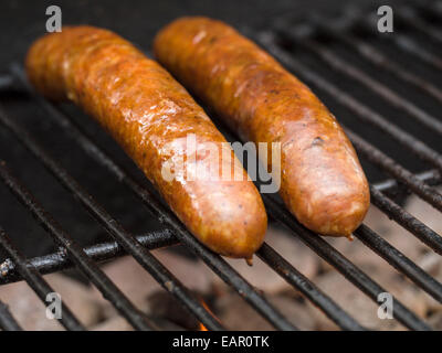 Deux saucisses du chauffage. Deux grandes saucisses sur un barbecue chauffage. La lueur de la braise vient de ci-dessous. Banque D'Images