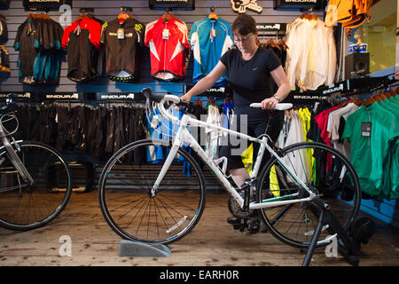 Une femme essayant un vélo lors de cycles de sommet, une petite réparation et vente de bicyclettes indépendants, centre d'Aberystwyth, UK Banque D'Images