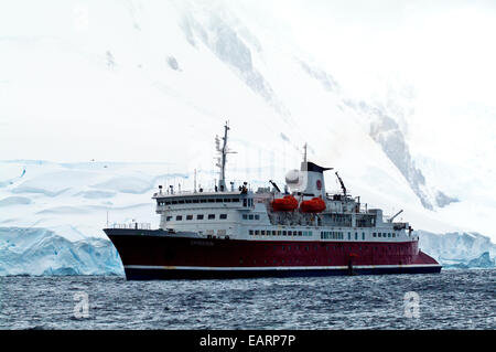 Une croisière antarctique navire ancré par un pic incrustés de la neige et de la glace. Banque D'Images